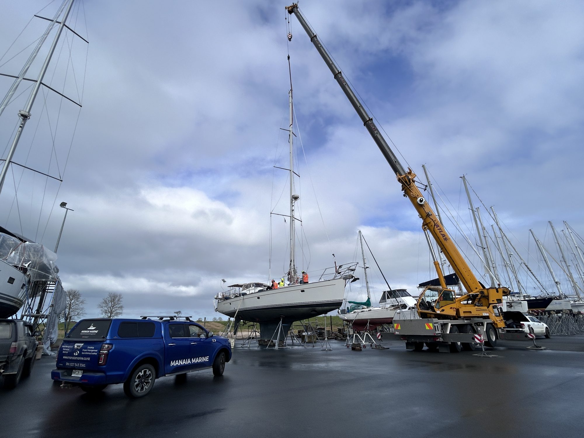 Yacht being lifted by crane in a Northland boatyard with the Manaia Marine ute alongside